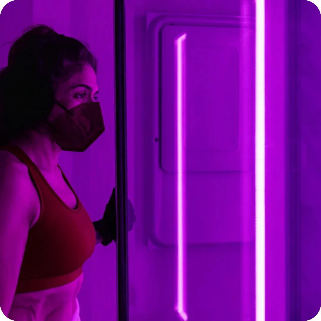Client standing in a modern cryotherapy chamber with cool ambient lighting